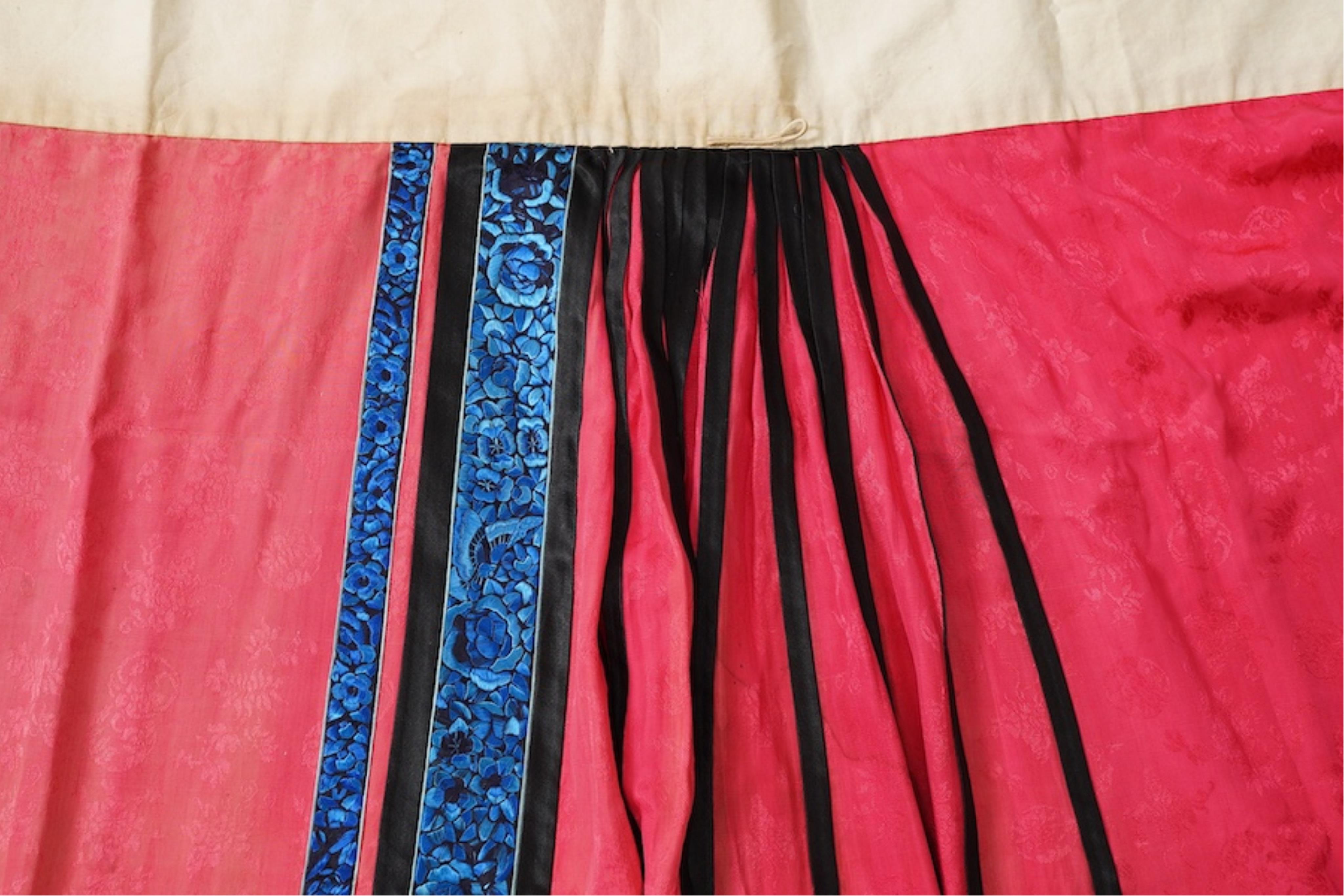 Two late 19th early 20th century Chinese wedding skirts. Made with pink silk damask, embroidered with large decorative silk floral and butterfly front panels bordered by blue embroidered black silk borders between pleats